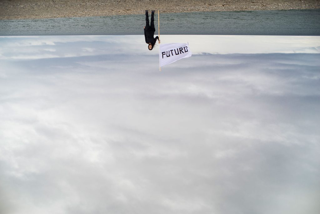 La artista performance Marcela Moraga Millán sosteniendo una bandera que dice "Futuro".